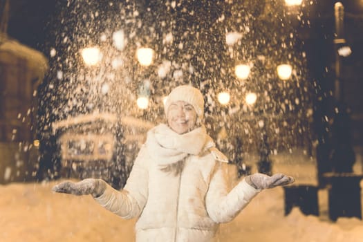 Girl having fun christmas decoration lights street. Young happy smiling woman wearing stylish knitted scarf and jacket outdoors. Model laughing. Winter wonderland city scene, New Year party.