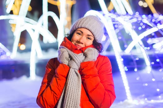 Winter holiday season. Christmas, New Year concept. Funny woman spend time having fun near illuminated and decorated showcase on city street.