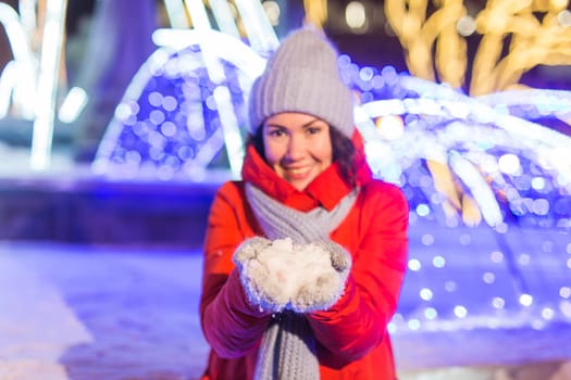 Happy funny young woman with winter clothes background evening city lights illumination. Christmas and winter holidays.