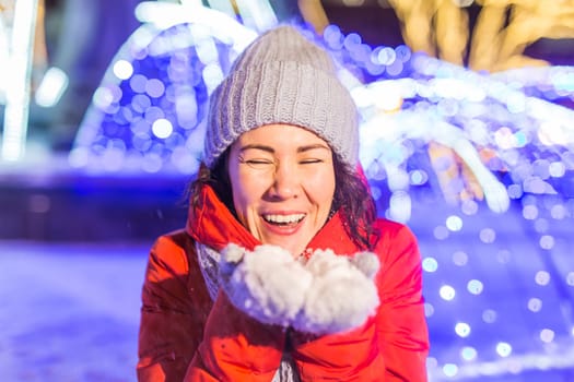 Happy funny young woman with winter clothes background evening city lights illumination. Christmas and winter holidays.
