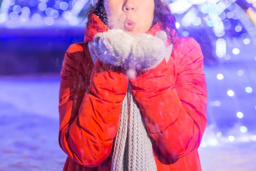 Girl having fun christmas decoration lights street. Young happy smiling woman wearing stylish knitted scarf and jacket outdoors. Model laughing. Winter wonderland city scene, New Year party.