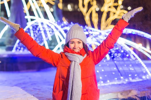 Winter holiday season. Christmas, New Year concept. Funny woman spend time having fun near illuminated and decorated showcase on city street.