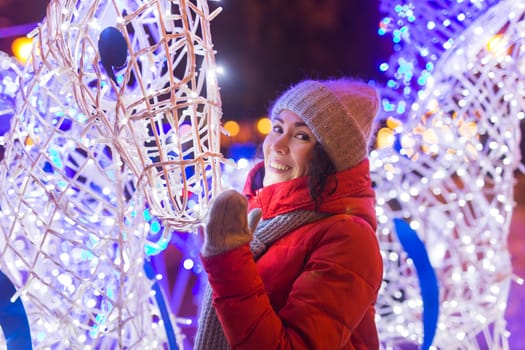 Portrait of young funny attractive woman over snowy Christmas background. Winter holidays and season.