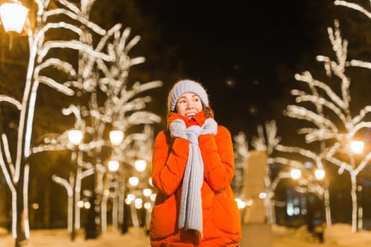 Winter holiday season. Christmas, New Year concept. Funny woman spend time having fun near illuminated and decorated showcase on city street.