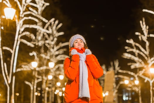 Winter holiday season. Christmas, New Year concept. Funny woman spend time having fun near illuminated and decorated showcase on city street.