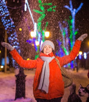 Winter holiday season. Christmas, New Year concept. Funny woman spend time having fun near illuminated and decorated showcase on city street.