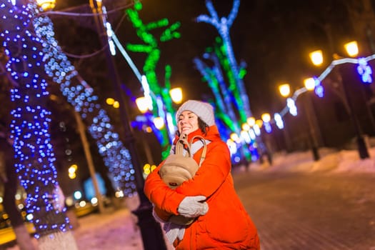 Winter holiday season. Christmas, New Year concept. Funny woman spend time having fun near illuminated and decorated showcase on city street.