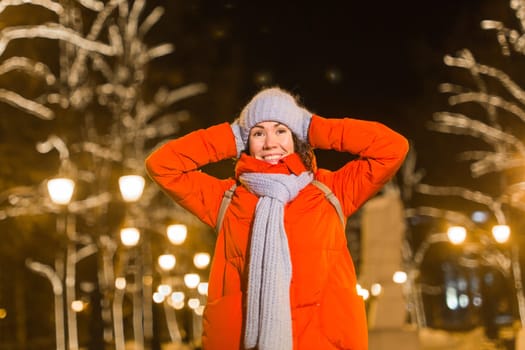 Winter holiday season. Christmas, New Year concept. Funny woman spend time having fun near illuminated and decorated showcase on city street.