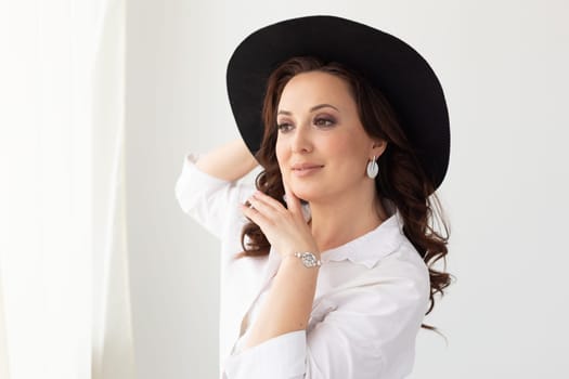 Portrait of a beautiful graceful woman in elegant hat with a wide brim. Beauty and fashion concept