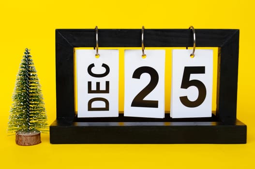 25 December calendar with Christmas trees on yellow background. Christmas season concept.