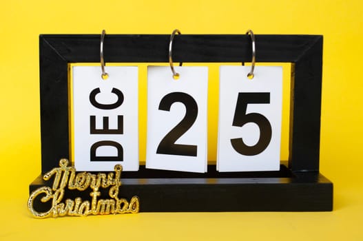 25 December calendar with Christmas wishes on yellow background. Christmas season concept.