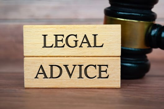 Legal Advice text on wooden blocks with gavel background. Legal Advice concept.