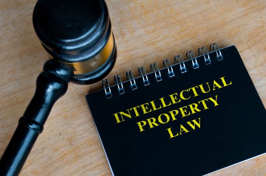 Top view of black notebook with text Intellectual Property Law and with gavel background.
