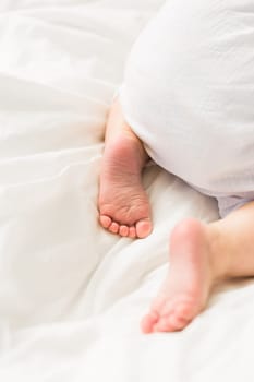 New born baby feet on white blanket on bedroom top view. Child and innocence.