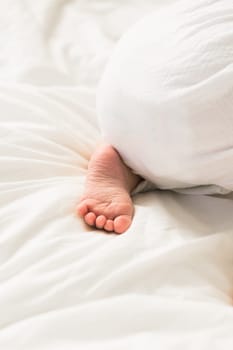 New born baby feet on white blanket on bedroom top view. Child and innocence.