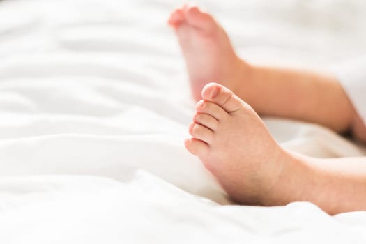 New born baby feet on white blanket on bedroom top view. Child and innocence.