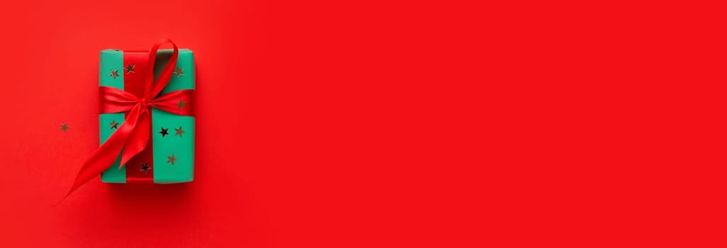 Christmas composition . Christmas gift on the red background . Green box with red ribbon .Flat lay . Top view . Mockup . Copy space .Free space .