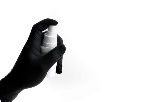 Hand in black nitrile glove holds spray for disinfection. free space for text.