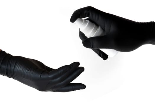 The hand of one person in a black latex glove sprays a disinfectant on the hands of another unprotected person to prevent infection during the Covid-19 epidemic and protect health. High quality photo