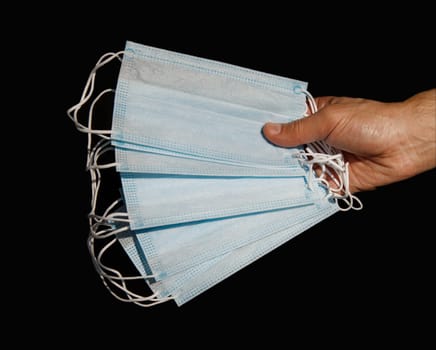 male hand holding several disposable medical masks. selective focus