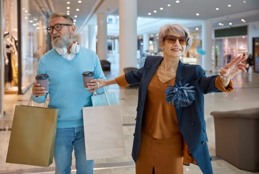 Senior husband and wife going shopping on black friday weekends. Excited elderly woman asking loving spouse for more purchases