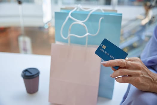 Closeup senior female hand holding credit card for shopping contactless payment. Finance, security and cashback for purchases