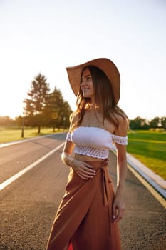 Portrait of charming young hipster woman in straw hat over road. Travel, trip adventure and outdoor recreation time concept