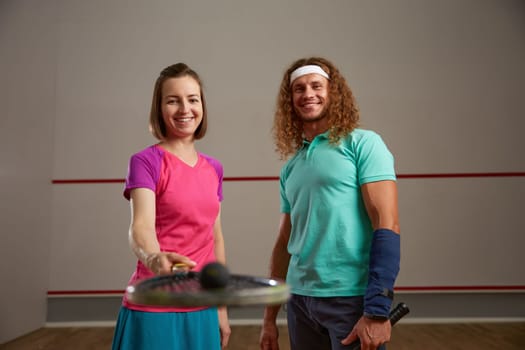 Happy couple posing for camera after squash game. Motivation and effort training concept