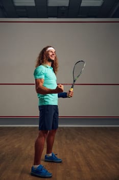 Portrait of satisfied squash player clenching fist rejoicing win in game or successful end of training