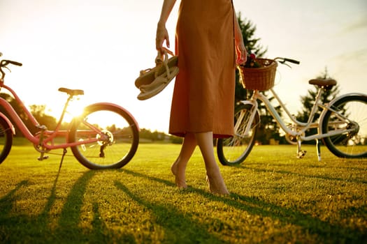 Closeup barefoot young female bicyclist on park grass lawn. Healthy lifestyle, active leisure time and unity with nature concept