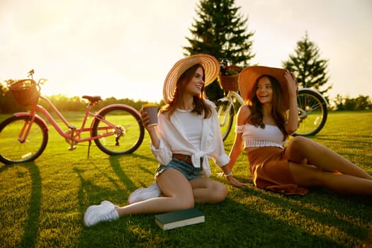 Two young hipster women taking rest having coffee break after active bike race. Girlfriend relations and happy weekends