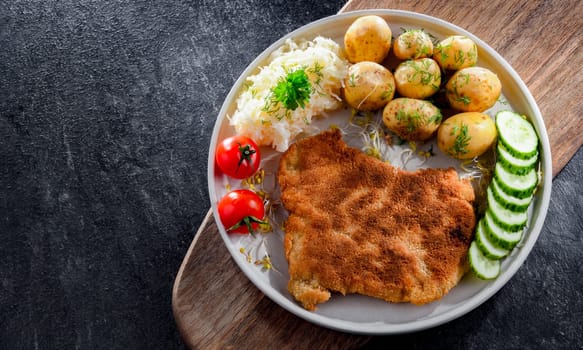 Pork breaded cutlet coated with breadcrumbs served with potatoes and cabbage
