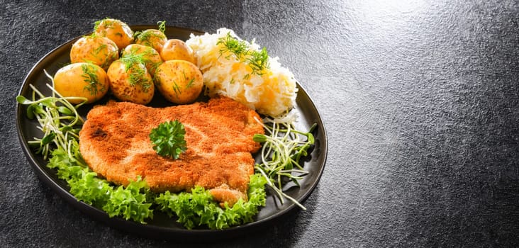 Pork breaded cutlet coated with breadcrumbs served with potatoes and cabbage