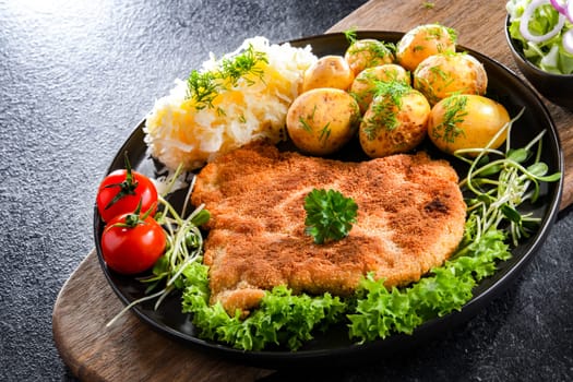 Pork breaded cutlet coated with breadcrumbs served with potatoes and cabbage