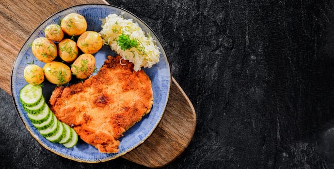 Pork breaded cutlet coated with breadcrumbs served with potatoes and cabbage