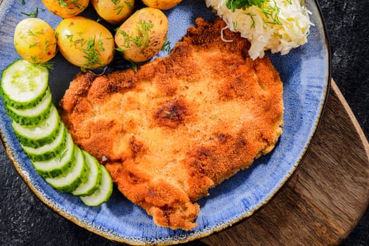 Pork breaded cutlet coated with breadcrumbs served with potatoes and cabbage
