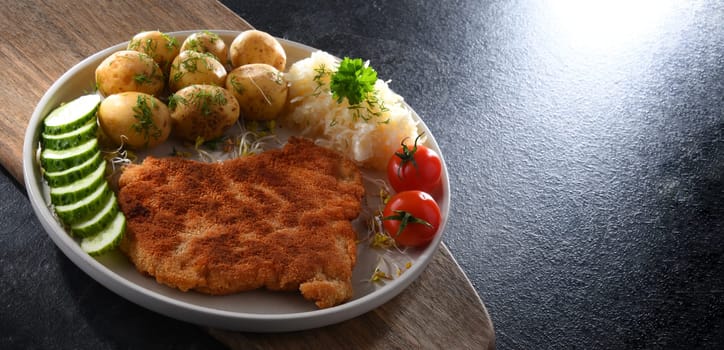 Pork breaded cutlet coated with breadcrumbs served with potatoes and cabbage