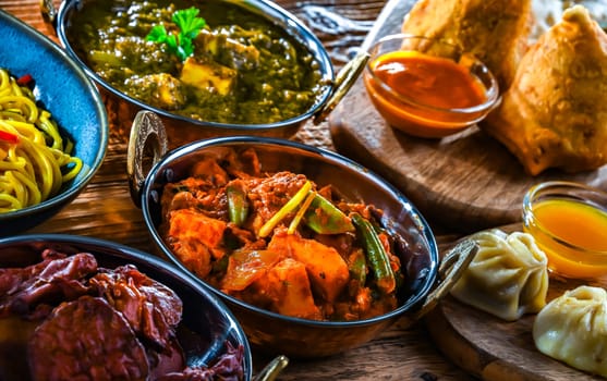 Composition with indian dishes: samosa, pakora, palak paneer, jalfrezi, thukpa and naan bread