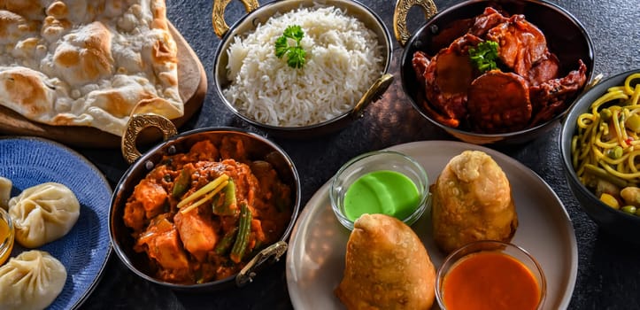 Composition with indian dishes: samosa, pakora, palak paneer, jalfrezi, thukpa and naan bread