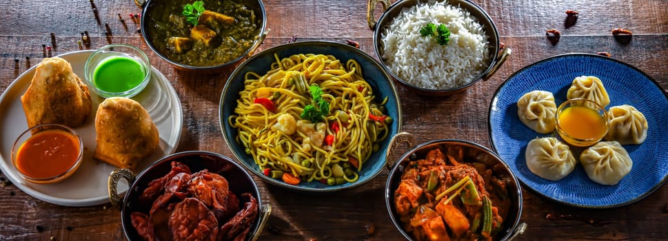 Composition with indian dishes: samosa, pakora, palak paneer, jalfrezi, thukpa and naan bread