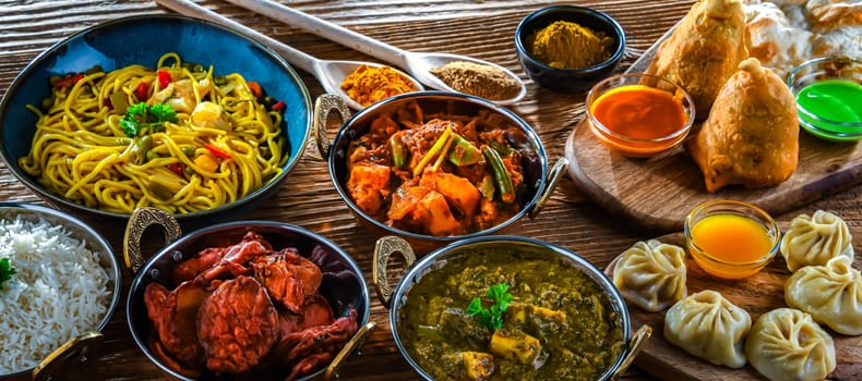 Composition with indian dishes: samosa, pakora, palak paneer, jalfrezi, thukpa and naan bread