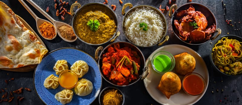 Composition with indian dishes: samosa, pakora, palak paneer, jalfrezi, thukpa and naan bread