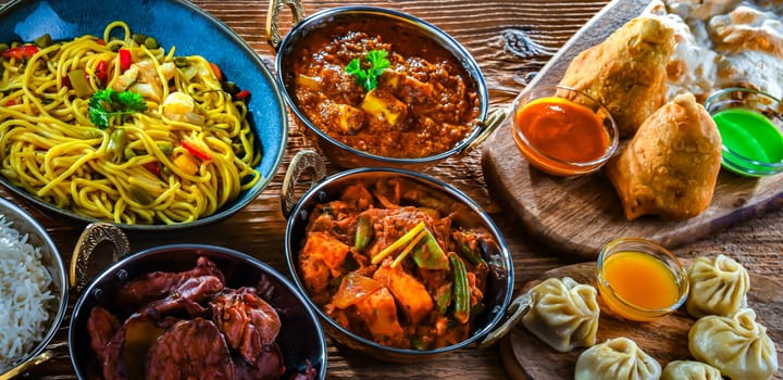 Composition with indian dishes: samosa, pakora, palak paneer, jalfrezi, thukpa and naan bread