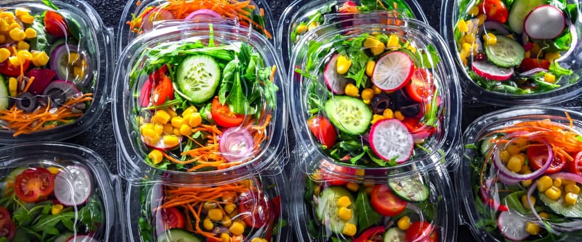 Plastic boxes with pre-packaged vegetable salads, put up for sale in a commercial refrigerator