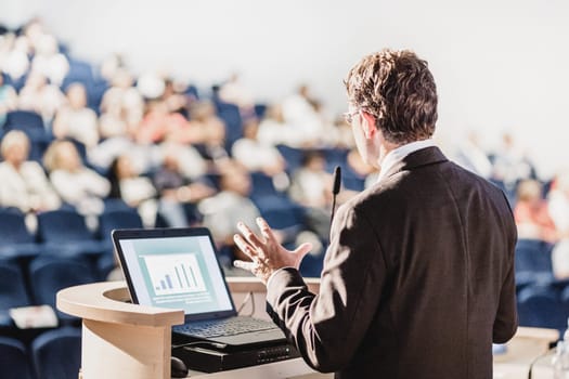 Speaker at Business Conference with Public Presentations. Audience at the conference hall. Entrepreneurship club. Rear view. Horisontal composition. Background blur.
