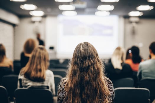 Speaker giving a talk in conference hall at business event. Rear view of unrecognizable people in audience at the conference hall. Business and entrepreneurship concept