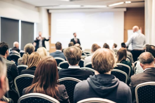 I have a question. Group of business people sitting at the chairs in conference hall. Businessman standing up asking a question. Conference and Presentation. Business and Entrepreneurship.