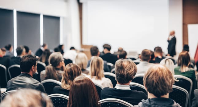 Speaker giving a talk in conference hall at business event. Rear view of unrecognizable people in audience at the conference hall. Business and entrepreneurship concept