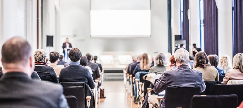 Speaker giving a talk in conference hall at business event. Rear view of unrecognizable people in audience at the conference hall. Business and entrepreneurship concept