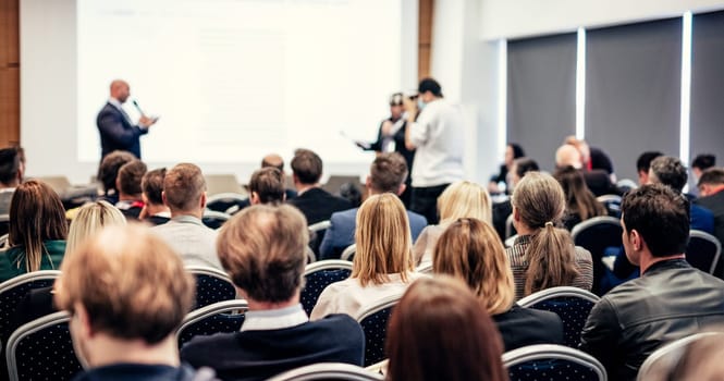 I have a question. Group of business people sitting at the chairs in conference hall. Businessman standing up asking a question. Conference and Presentation. Business and Entrepreneurship.
